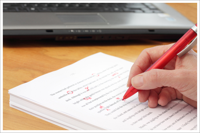 Person editing a paper with a red pen